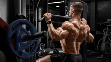 A muscular person working out in the gym doing lat pulldown exercise.