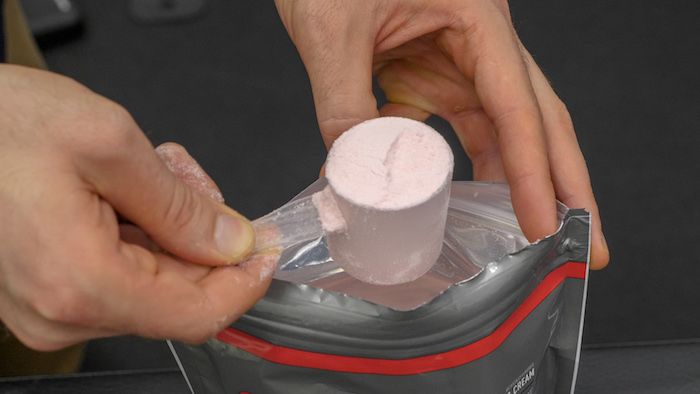 A BarBend tester scooping out supplement powder for testing.