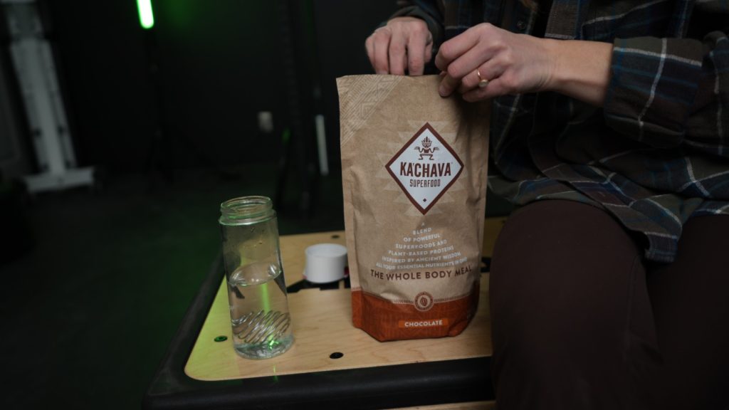 A BarBend tester opening a bag of Ka'Chava Whole Body Meal.