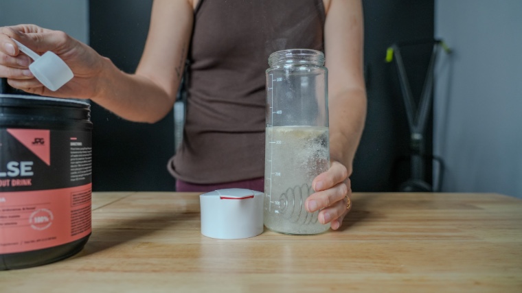 Our tester dumps a scoop of Legion Pulse Pre-Workout into a shaker bottle.