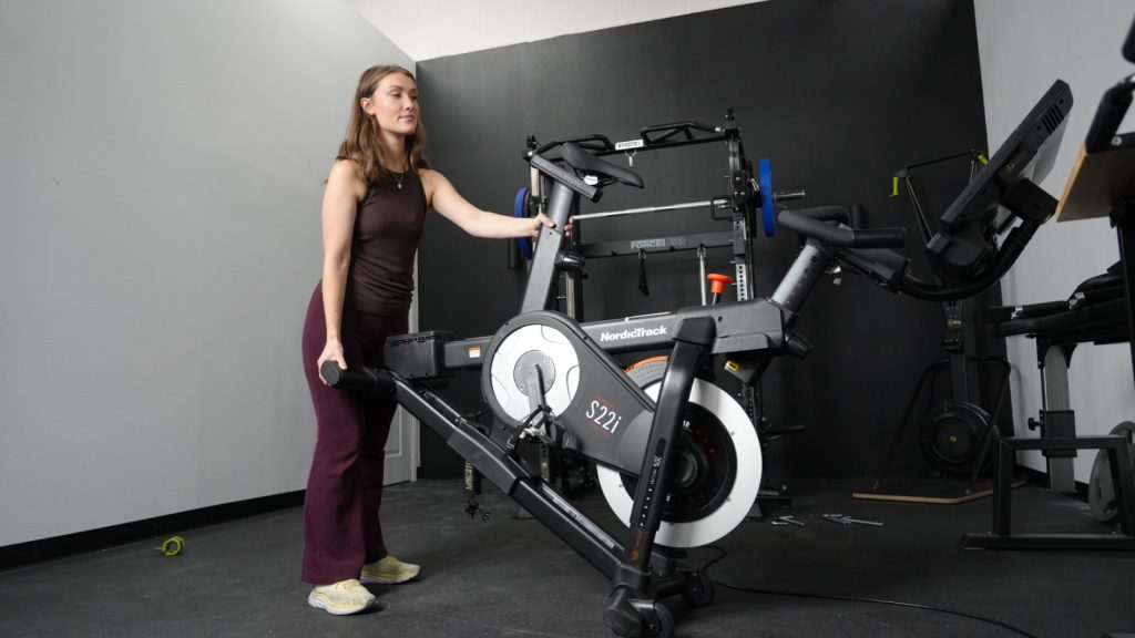 A BarBend tester moving the NordicTrack S22i exercise bike.