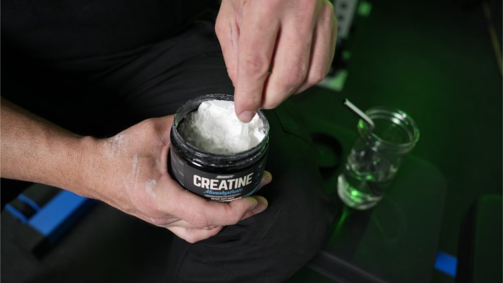 A BarBend tester scooping Onnit creatine.