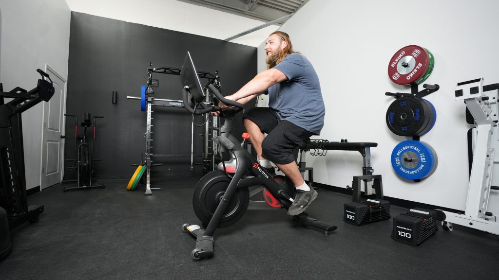 A BarBend tester riding on a Peloton exercise bike.