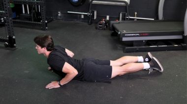 Jake demonstrating the pilates swan, a pilates for beginners movement.