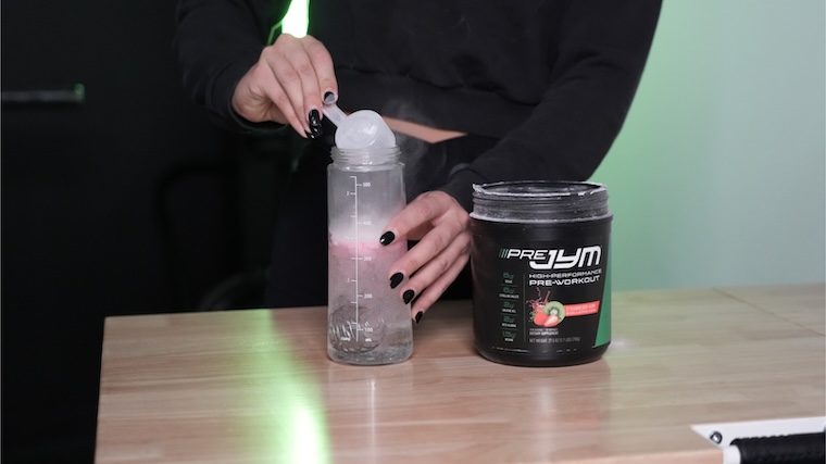 Our tester dumping a scoop of JYM Pre-JYM pre-workout into a shaker bottle