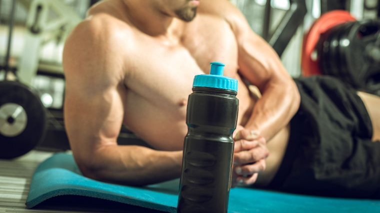 A shirtless person lies on their side in the gym.