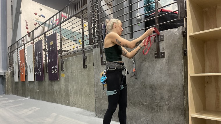 A climber using the red Titan Fitness Light Resistance Band.