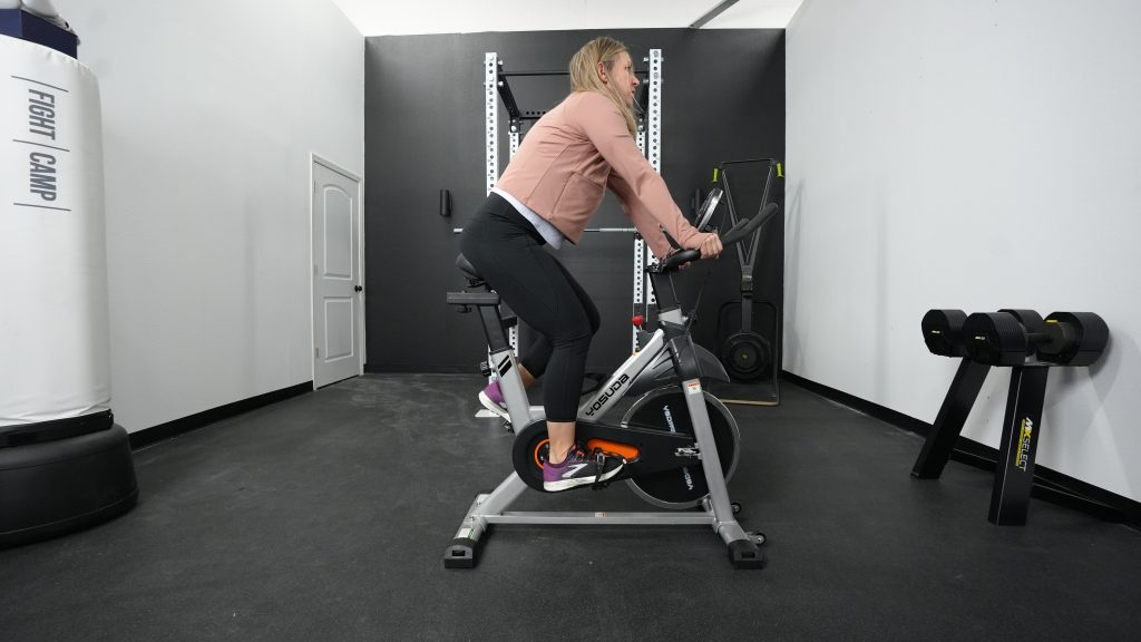 A BarBend tester riding a Yosuda YB001R exercise bike.