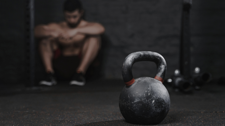 athlete sitting on the floor feeling tired in the gym