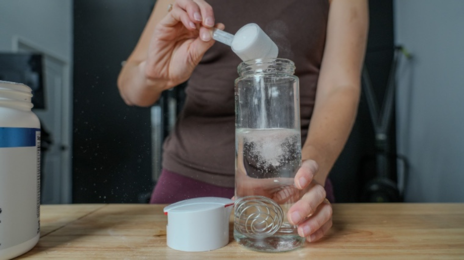 Putting a powdered supplement into a shaker with water.