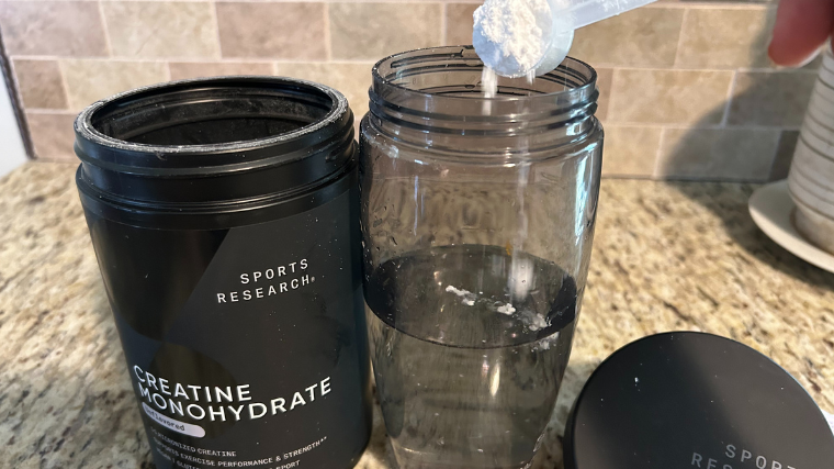 A BarBend tester trying a scoop of Sports Research creatine.